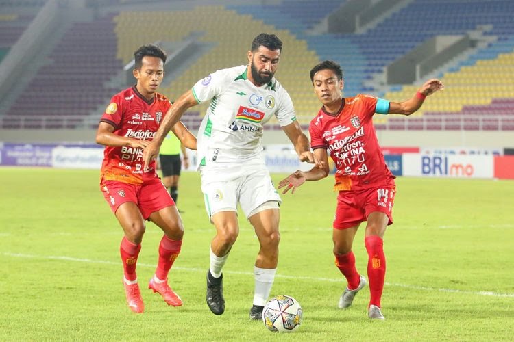 Pemain PSS Sleman Jihad Ayoub (tengah) diapit oleh dua personel Bali United dalam laga pekan ke-16 Liga 1 2022-2023 antara Bali United vs PSS Sleman di Stadion Manahan, Solo.