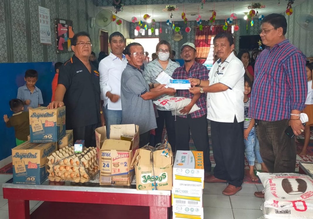 Ketua panitia Natal PWI Sumut Proklamasi Naibaho menyerahkan bantuan Natal kepada Pimpinan PA Anugerah Kasih Abadi Resmond Simanjuntak di dekat Perumahan PWI.