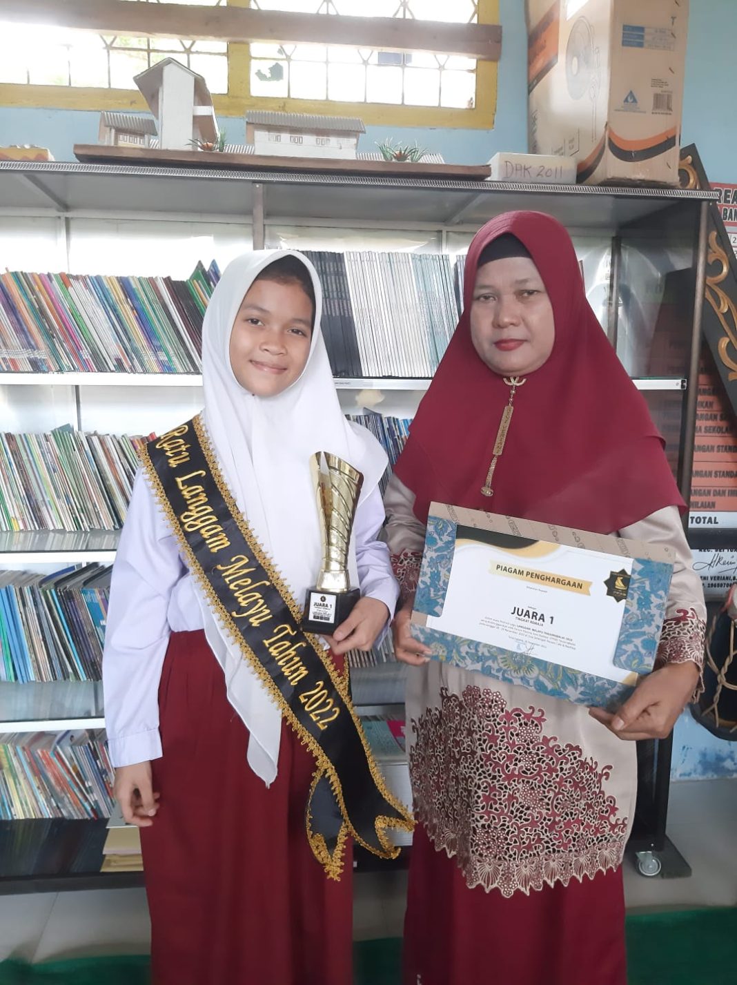 Zahratul Saddah siswi SDN 130003 dengan merangkul tropy juara, berfoto bersama Kepala Sekolah Reni Veriani di ruang kelas, Rabu (7/12/2022).