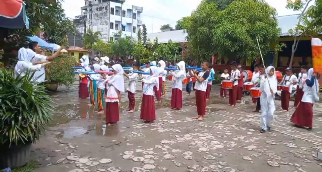 Grup drum band SD Negeri 132406 Kota Tanjungbalai sedang berlatih di halaman sekolah.