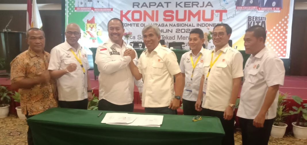 Kadispora Sumut Baharuddin Siagian berjabat tangan dengan Ketua KONI Sumut John Ismadi Lubis saat membuka Rapat Kerja KONI Sumut di Emerald Garden Internasional Hotel Medan.