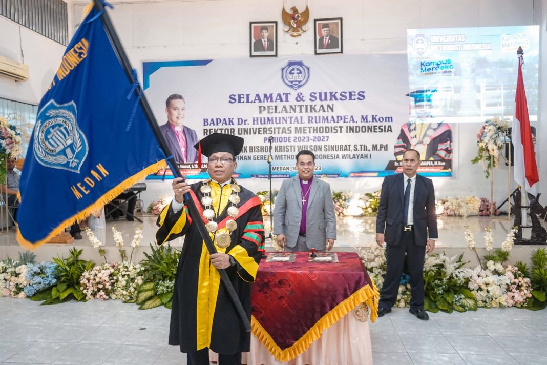 Dr Humuntal Rumapea MKom mengibarkan pataka usai dilantik menjadi Rektor UMI periode 2023-2027 oleh Bishop GMI Wilayah I.