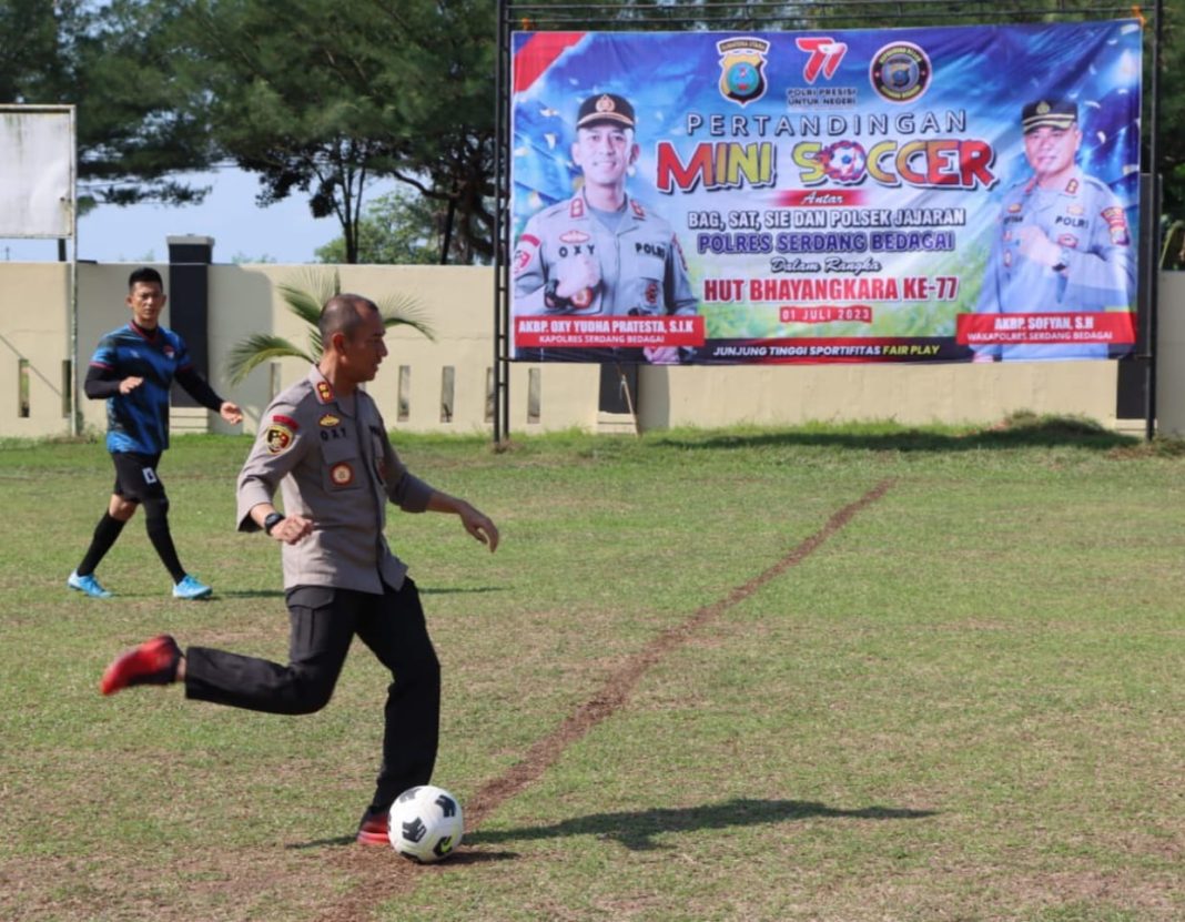 Kapolres Sergai AKBP Oxy Yudha Pratesta melakukan tendangan kick off pertama tanda dimulainya pertandingan mini soccer yang digelar Polres Sergai dalam rangka memeriahkan HuT ke-77 Bhayangkara, Senin (5/6/2023). (Dok/Humas Polres Sergai)