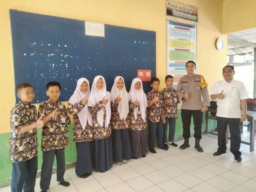 Personel Bhabinkamtibmas Polsek Pangkalan Susu Brigadir Rico Surya Ardana foto bersama dengan para pelajar dan pengajar dalam kegiatan sambang di Sekolah Desa Salahaji, Kecamatan Pematang Jaya, Kabupaten Langkat, Jumat (7/7/2023). (Dok/Humas Polres Langkat)