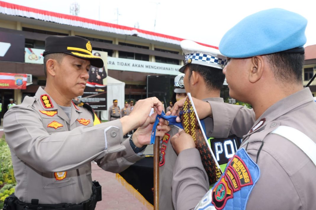 Kapolrestabes Medan Kombes Pol Valentino Alfa Tatareda SH SIK menyematkan pita ke pundak personel yang tersprin Ops Patuh Toba 2023, di Mapolrestabes, Senin (10/7/2023). (Dok/Polrestabes Medan)