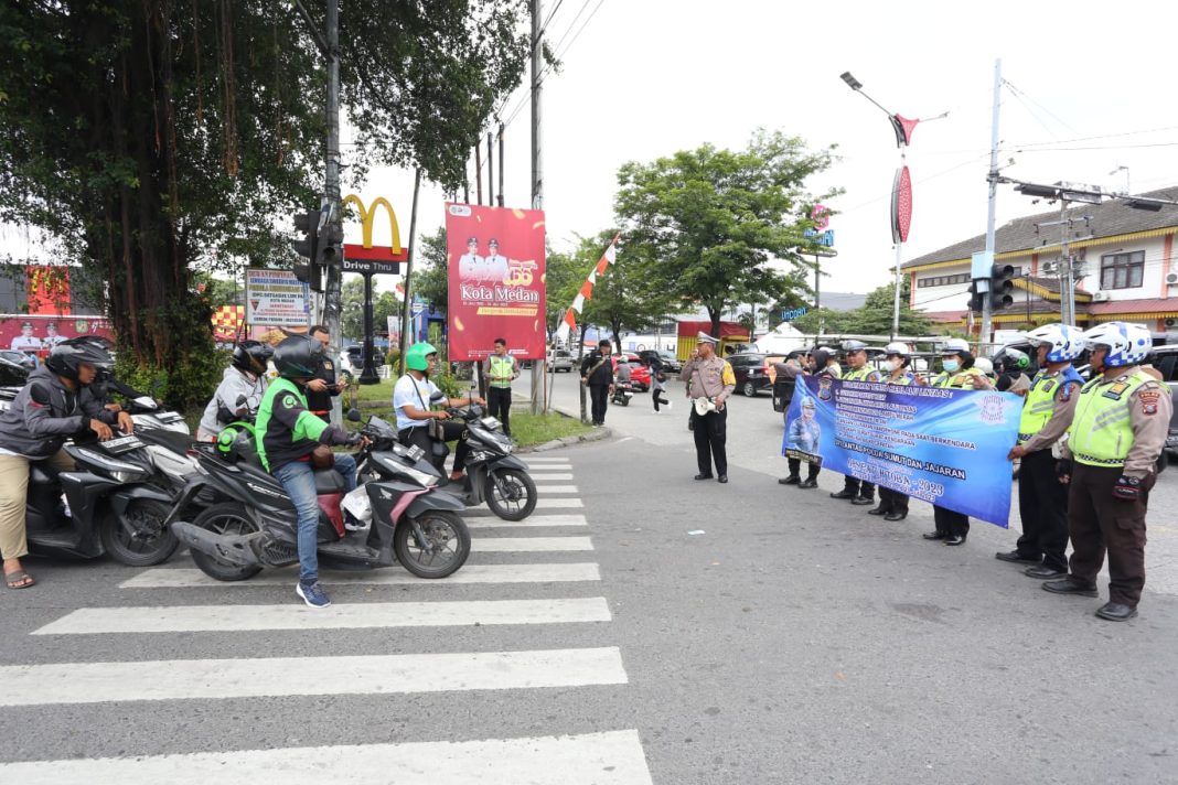 Personel lantas membentangkan spanduk berisi himbauan kepada pengguna jalan di Persimpangan Jalan Pelangi Medan pada Ops Patuh Toba 2023, Senin (10/7/2023). (Dok/ Polda Sumut)