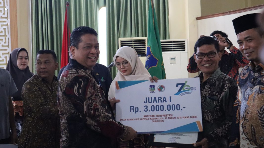 Pj Wali Kota Tebingtinggi Syarmadani menyerahkan hadiah kepada koperasi yang berprestasi, di Gedung Hj Shawiyah, Jumat (21/7/2023). (Dok/Kominfo Tebingtinggi)