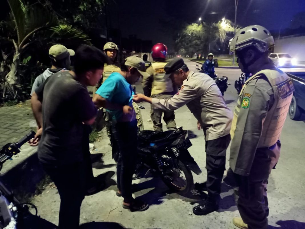 Saat menggelar patroli, personel Polsek Percut Sei Tuan melakukan pemeriksaan di badan pria yang dianggap mencurigakan, Minggu (23/7/2023). (Dok/Polsek Percut Sei Tuan)