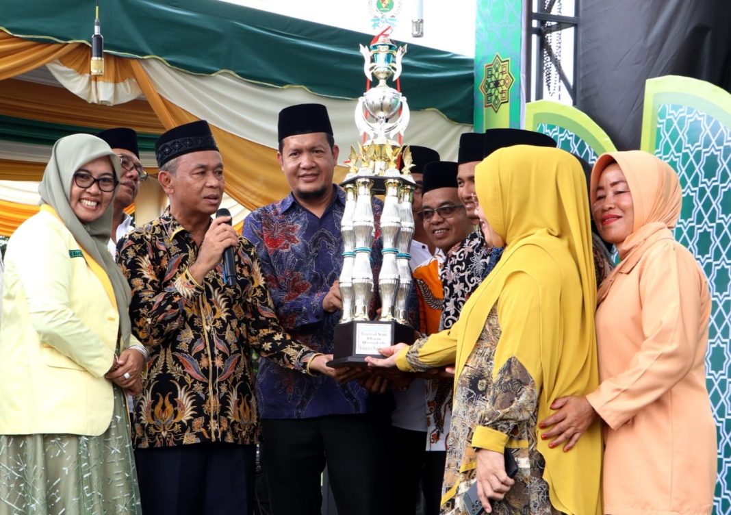 Asisten Perekonomian dan Pembangunan Simalungun Ramadhani Purba menyerahkan piala kepada juara umum Festival Seni dan Qasidah di Lapangan Rintis VII PTPN IV Kebun Balimbingan, Sabtu (29/7/2023) petang. (Dok/Kominfo Simalungun)