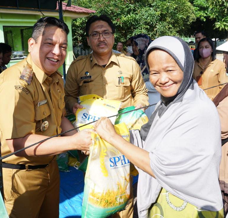 Pj Wali Kota Tebingtinggi Syarmadani didampingi Kepala Dinas Perdagangan, Koperasi dan UKM Zahidin menyerahkan beras kepada warga, di Lapangan Merdeka, Jalan Sutomo, Selasa (22/8/2023).