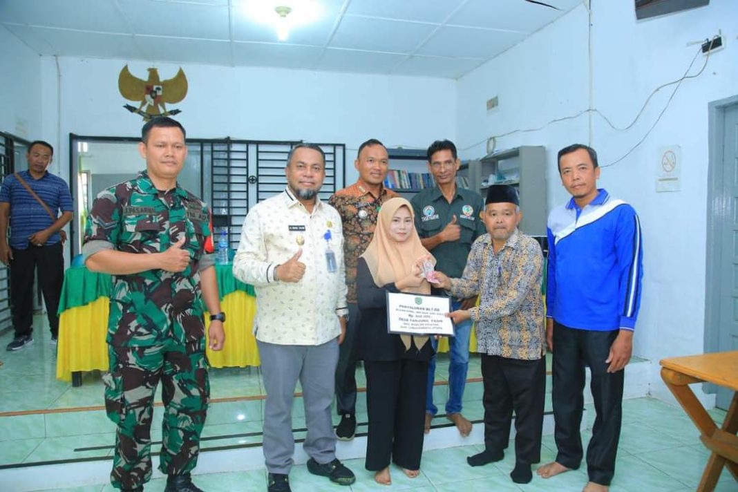 Plt Kades Tanjung Pasir Jahri Nasution disaksikan Sekda Labura HM Suib menyerahkan BLT DD kepada warga penerima bantuan di Desa Tanjung Pasir, Jumat (1/9/2023). (Dok/Kominfo Labura)