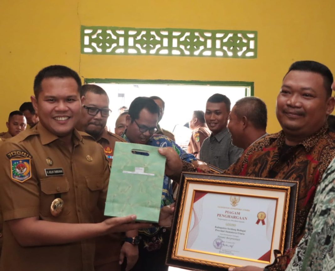 Wabup Sergai H Adlin Tambunan menyerahkan penghargaan kepada Legino, juara II kategori petani berprestasi tingkat Sumut, Selasa (5/9/2023). (Dok/Kominfo Sergai)
