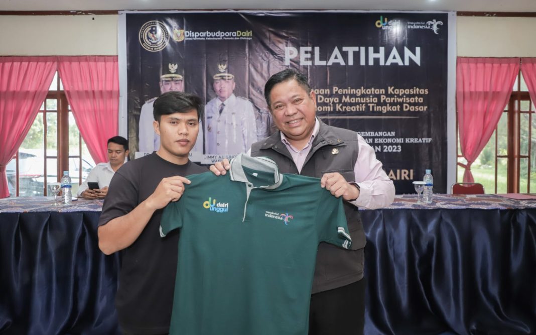 Bupati Dairi Eddy KA Berutu menyerahkan baju kepada peserta pelatihan SDM pariwisata dan ekonomi kreatif di Sidikalang, Senin (11/9/2023). (Dok/Kominfo Dairi)