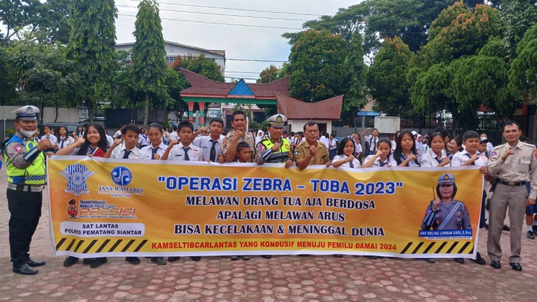 Personel Satlantas Polres Pematangsiantar foto bersama siswa/i usai melaksanakan sosialiasi di SMPN 7 Kota Pematangsiantar, Selasa (12/9/2023). (Dok/Humas Polres Pematangsiantar)