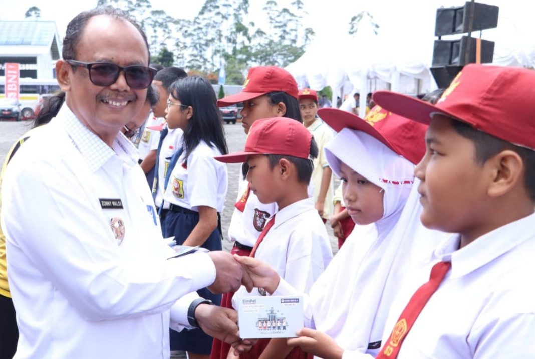 Wakil Bupati Simalungun Zonny Waldi memberikan buku tabungan kepada pelajar saat acara Bulan Inklusi Keuangan di Pamatangraya, Rabu (25/10/2023).