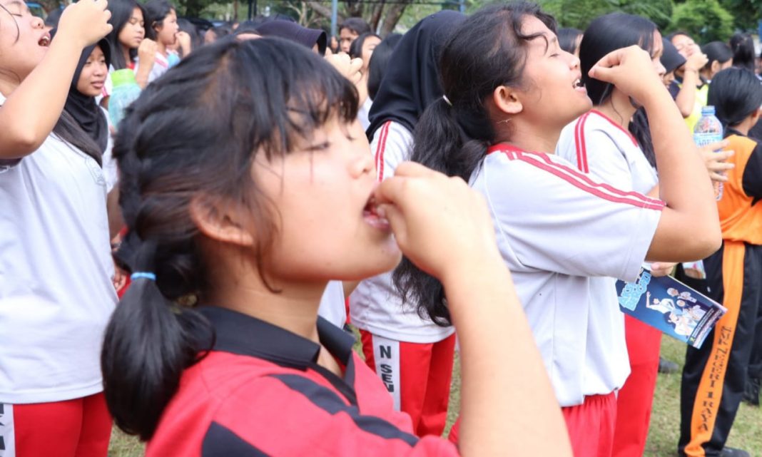 Remaja putri mengonsumsi tablet tambah darah pada acara gerakan masyarakat hidup sehat melalui program aksi bergizi, di SMK Negeri 1 Raya, Jumat (13/10/2023). (Dok/Kominfo Simalungun)