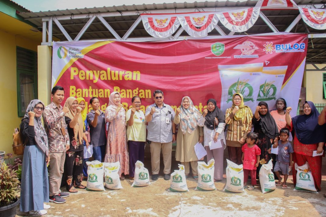 Plh Sekda Kota Padangsidimpuan H Rahuddin Harahap SH MH foto bersama warga penerima bantuan pangan cadangan beras tahap 2 di Aula Kantor Camat Padangsidimpuan Tenggara, Kota Padangsidimpuan, Jumat (13/10/2023). (Dok/Kominfo Padangsidimpuan)