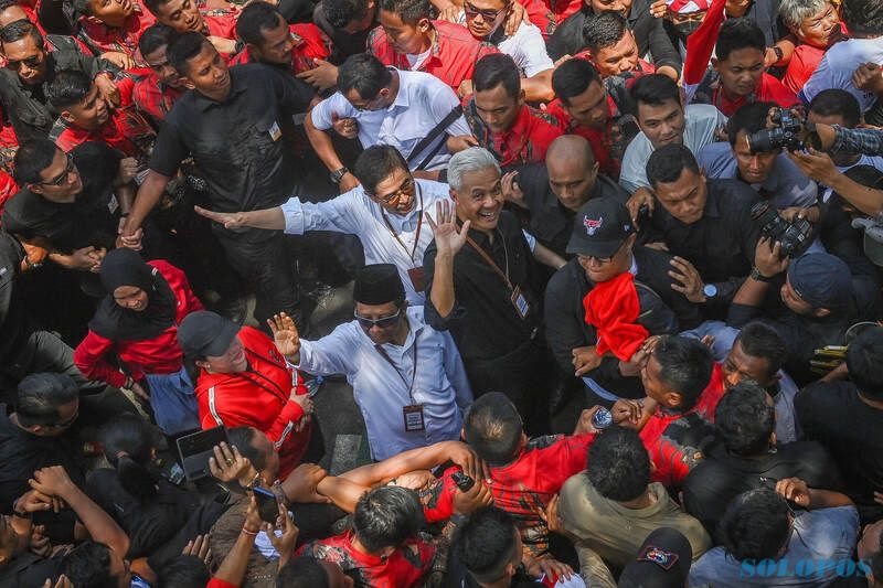 Bakal calon presiden Ganjar Pranowo (kanan) didampingi bakal calon wakil presiden Mahfud MD (kiri) bersama para pendukungnya tiba di Gedung KPU, Jakarta, Kamis (19/10/2023).