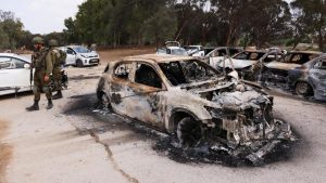 Tentara Israel memeriksa mobil-mobil yang terbakar yang ditinggalkan di tempat parkir di kawasan festival diadakan sebelum serangan oleh kelompok bersenjata Hamas dari Gaza yang menyebabkan sedikitnya 260 orang tewas, di perbatasan Israel dengan Gaza di Israel Selatan.