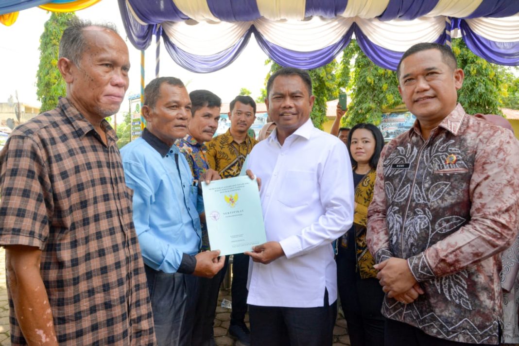 Bupati Sergai H Darma Wijaya didampingi Kepala Kantor BPN Sergai Roni LP Sitanggang secara simbolis menyerahkan sertifikat tanah kepada perwakilan masyarakat penerima, Jumat (3/11/2023). (Dok/Kominfo Sergai)