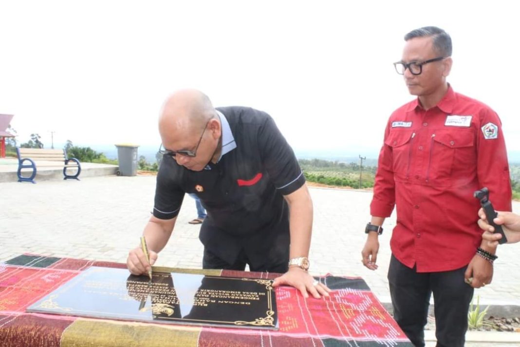 Bupati Taput Dr Nikson Nababan didampingi Kadis Pariwisata Taput Sasma Situmorang menandatangani prasasti peresmian pengembangan dan pembangunan DTW Salib Kasih di Desa Simorangkir Julu, Kecamatan Siatas Barita, Rabu, (22/11/2023). (Dok/Kominfo Taput)