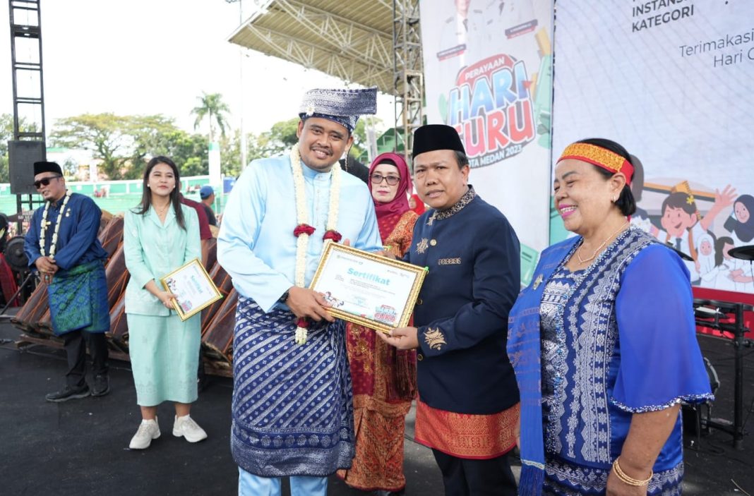 Wali Kota Medan Bobby Nasution menyerahkan penghargaan usai upacara peringatan Hari Guru Nasional tingkat Kota Medan di Stadion Teladan Medan, Sabtu (25/11/2023). (Dok/Kominfo Medan)