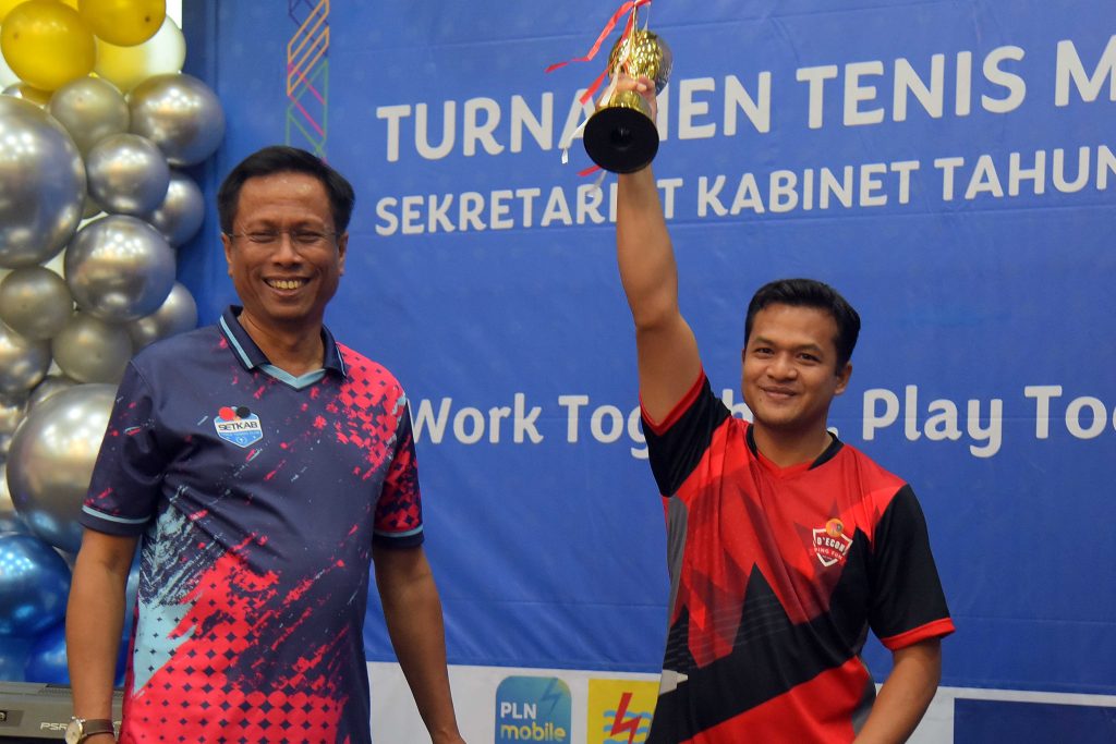 Deputi PMK Yuli Harsono menyerahkan Tropi kepada Iyus Suhendra sebagai Juara Tunggal Putra Turnamen Tenis Meja Setkab Tahun 2023, di Aula Gedung 3, Kemensetneg, Selasa (28/11/2023). (Dok/Humas Setkab)