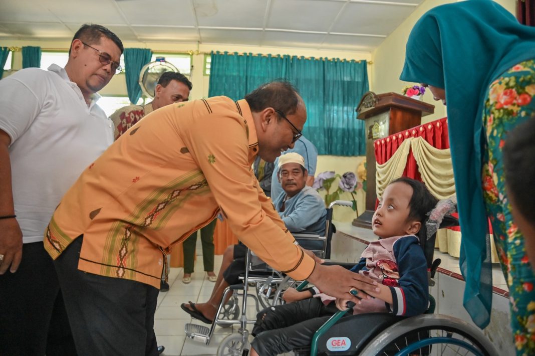 Pj Wali Kota Padangsidimpuan Dr H Letnan Dalimunthe SKM MKes sedang menyapa salah seorang anak difabel saat menyerahkan bantuan berupa bagi penyandang Disabilitas di Aula MAN 2 Padangsidimpuan, Jumat (3/11/2023). (Dok/Kominfo Padangsidimpuan)