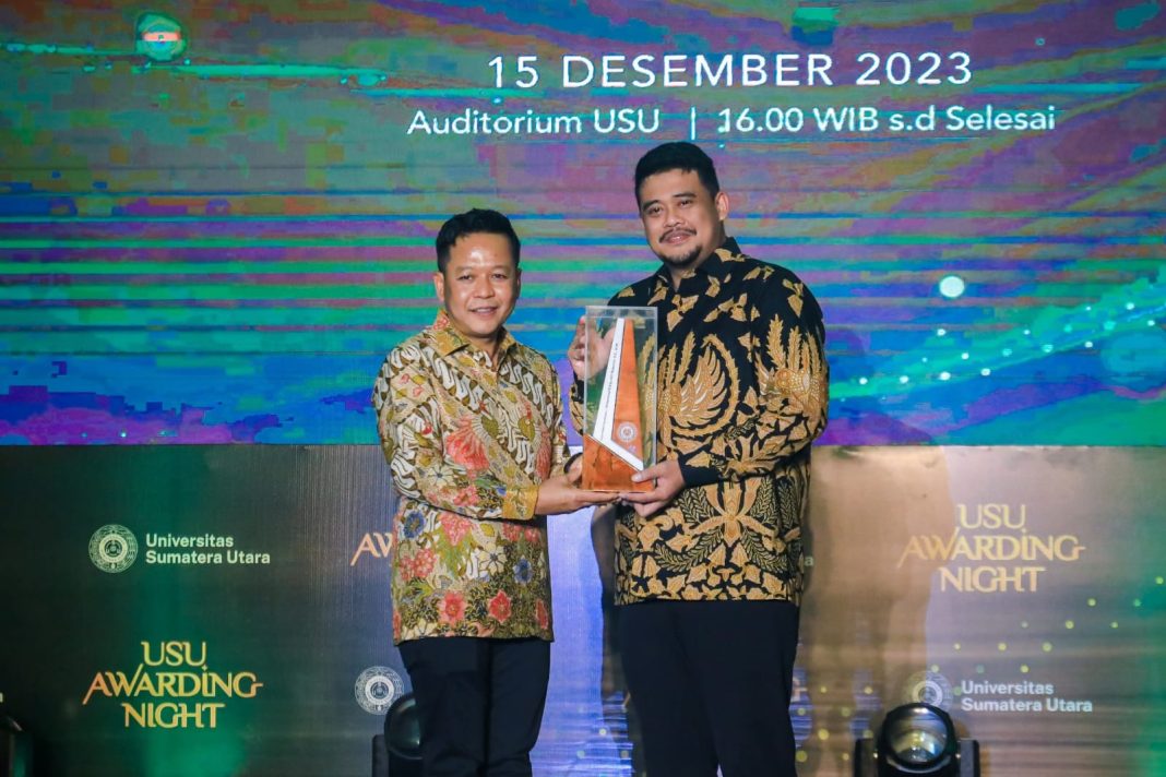 Rektor USU Muryanto Amin menyerahkan penghargaan kepada Wali Kota Medan Bobby Nasution di malam USU Awarding Night yang digelar di Auditorium USU, Jumat (15/12/2023). (Dok/Kominfo Medan)