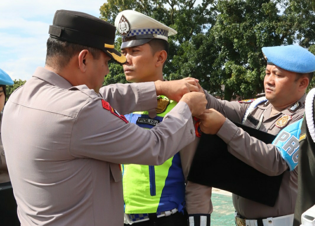 Wakapolres Pematangsiantar Kompol Pardamean Hutahaean menyempatkan pita kepada perwakilan petugas gabungan saat menggelar apel gelar pasukan Ops Lilin Toba 2023 di Lapangan Aspol Jalan Sangnaualuh, Kamis (21/12/2023). (Dok/Humas Polres Pematangsiantar)