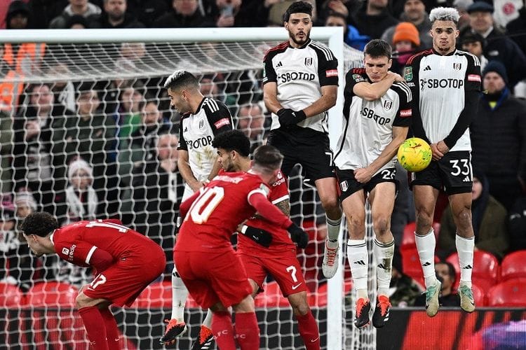 Gelandang Fulham Joao Palhinha (2 kanan) dan rekannya Andreas Pereira (kanan) melompat untuk memblok tendangan bebas gelandang Liverpool Alexis Mac Allister pada pertandingan leg pertama semifinal Piala Liga Inggris antara Liverpool vs Fulham di Anfield, Liverpool, Kamis (11/1/2024) dini hari WIB.