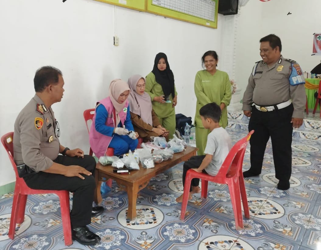 Kapolsek Tanjung Beringin AKP Tobat Sihombing menyaksikan tim medis memeriksa kesehatan anak warga pada pelaksanaan pelayanan kesehatan gratis, Selasa (16/1/2024). (Dok/Polsek Tanjung Beringin)