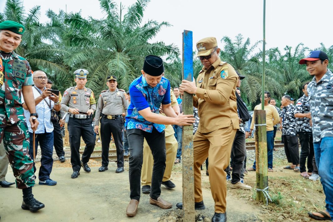 Pj Bupati Batubara Nizhamul SE MM (kanan) mencabut portal jalan yang berada di Area Perlintasan Kereta Api, Dusun 2, Desa Mekar Baru, Kecamatan Datuk Tanah Datar, Senin (29/1/2024). (Dok/Kominfo Batubara)