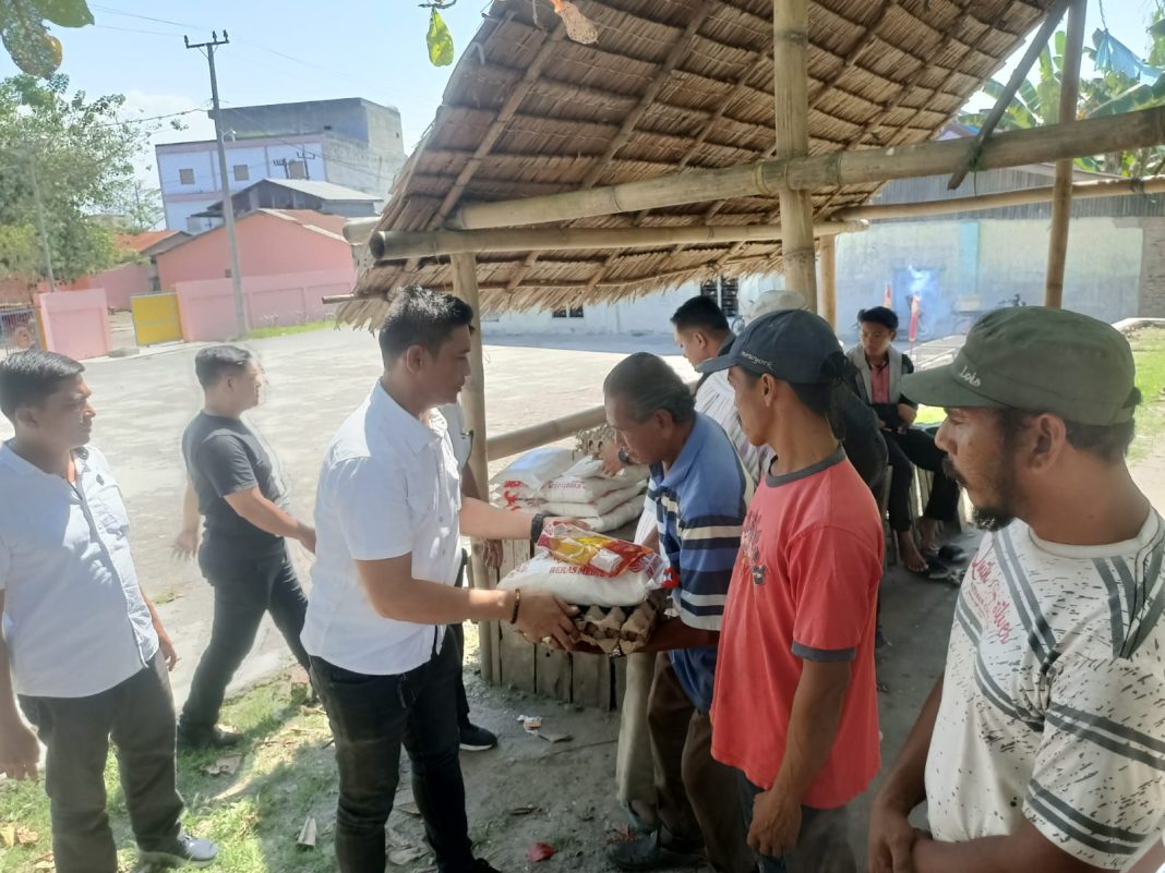 Kanit I Satnarkoba Polres Sergai Ipda Anggiat Sidabutar menyerahkan paket bantuan bahan pangan ke warga nelayan di Dusun I Desa Pantai Cermin Kiri, Kecamatan Pantai Cermin, Rabu (31/1/2024). (Dok/Humas Polres Sergai)