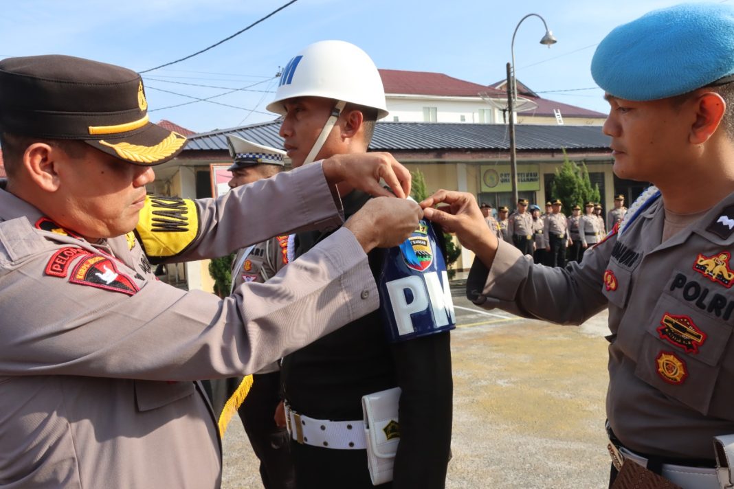 Wakapolres Pematangsiantar Kompol Pardamean Hutahaean, menyematkan pita kepada personel saat memimpin apel gelar pasukan Ops Keselamatan Toba 2024 di Lapangan Mapolres Pematangsiantar, Rabu (13/3/2024). (Dok/Humas Polres Pematangsiantar)