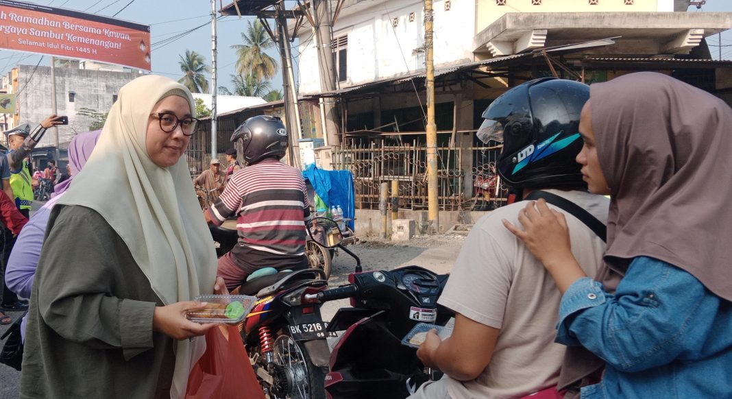 Hj Erlis Afriyanti saat membagikan takjil ke warga yang melintas di Jalan Thamrin, Sabtu (6/4/2024).