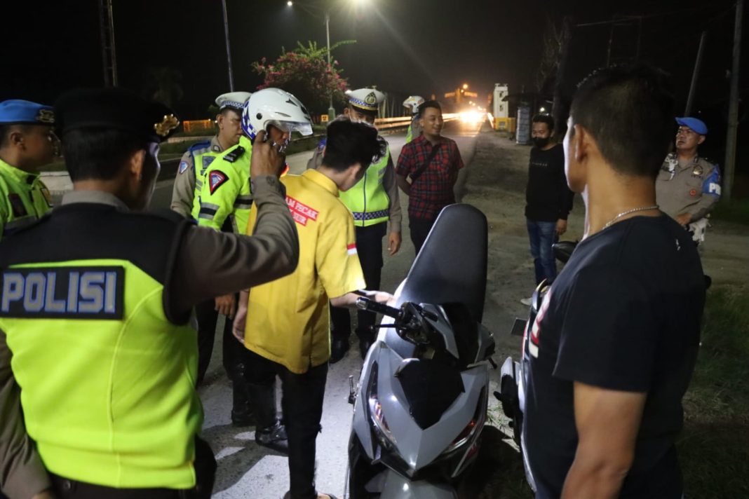 Personel gabungan Polres Sergai dan Polsek Perbaungan memeriksa kelengkapan surat-surat kendaraan dan barang bawaan pengendara sepeda motor guna mengantisipasi aksi kejahatan saat menggelar patroli dan razia KRYD, Sabtu (4/5/2024) malam. (Dok/Humas Polres Sergai)