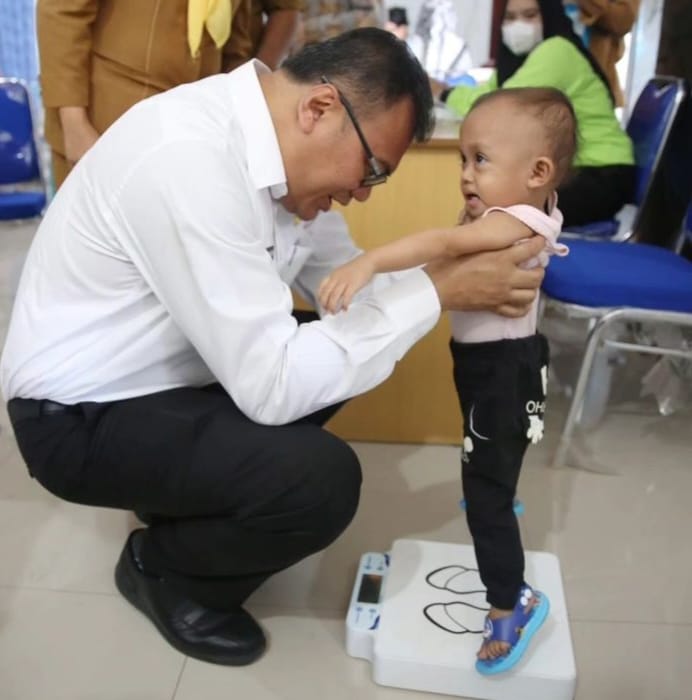 Kepala Dinas Kesehatan Deliserdang dr Asri Ludin menggendong seorang anak dalam kunjungan di Posyandu ILP di Tanjungmorawa, Selasa (7/5/2024).