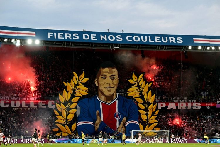Para pendukung bersorak di belakang tifo raksasa yang menggambarkan penyerang Paris Saint-Germain asal Perancis Kylian Mbappe sebelum pertandingan sepak bola Ligue 1 PSG dan Toulouse pada 13 Mei 2024 dini hari WIB di Stadion Parc des Princes, Paris.
