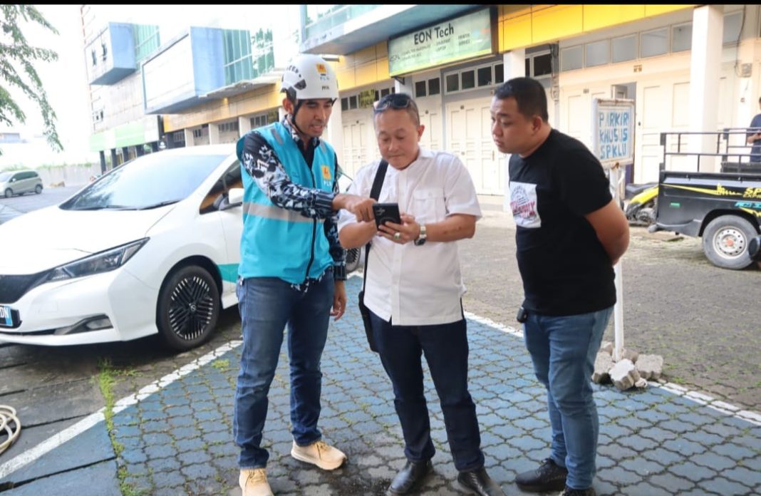 Manager PLN UP3 Medan Ricki Yakop (kiri) menjelaskan kepada Tonny pengguna kendaraan listrik (tengah) cara melakukan pengisian daya melalui aplikasi PLN Mobile di SPKLU City View, Sabtu (15/6/2024). (Dok/PLN)