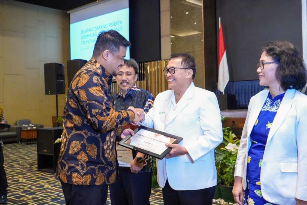Wali Kota Bobby Nasution menyerahkan cenderamata kepada para narasumber saat pelaksanaan Diseminasi Audit Kasus Stunting Semester I Tahun 2024, di Hotel Grand Mercure, Kamis (27/6/2024). (Dok/Kominfo Medan)