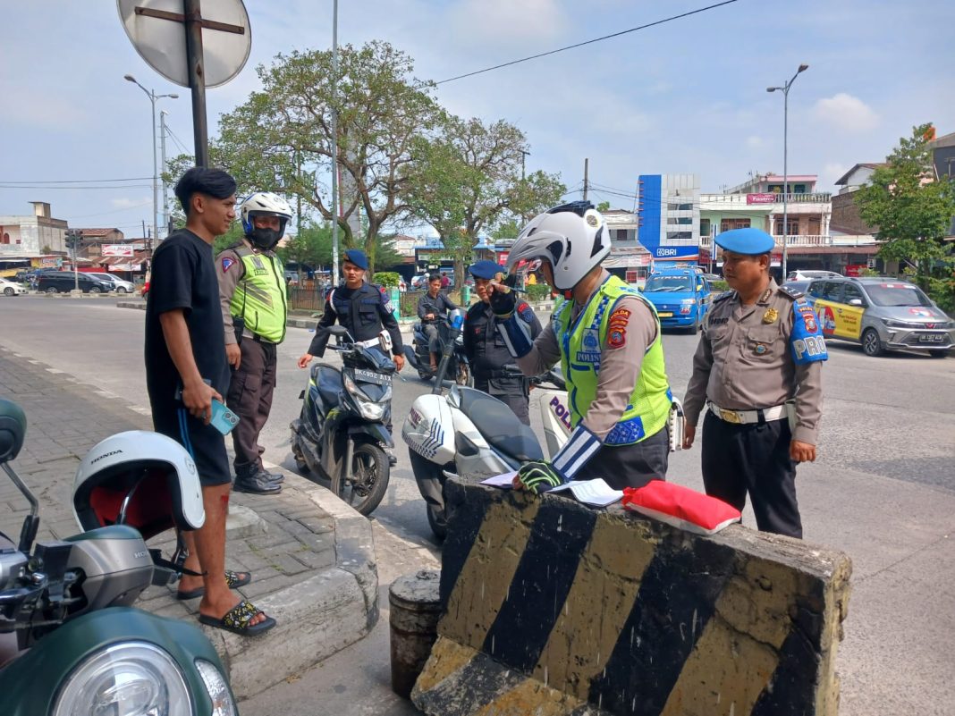 Polisi menilang pengendara sepeda motor yang tidak memakai helm pada Operasi Patuh Toba 2024 di bawah Fly Over Amplas, Selasa (16/7/2024). (Dok/Polda Sumut)