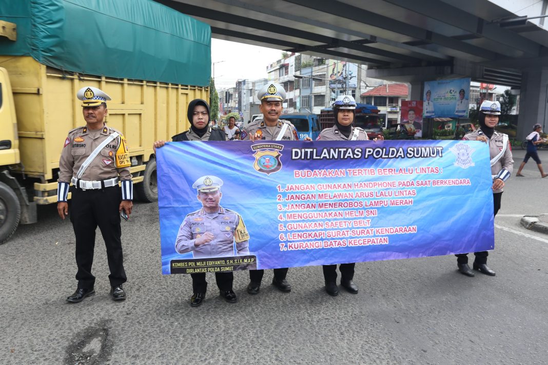 Polisi membentangkan spanduk berisi imbauan tertib berlalu lintas saat Operasi Patuh Toba 2024 di bawah Fly Over Amplas Medan. (Dok/Polda Sumut)