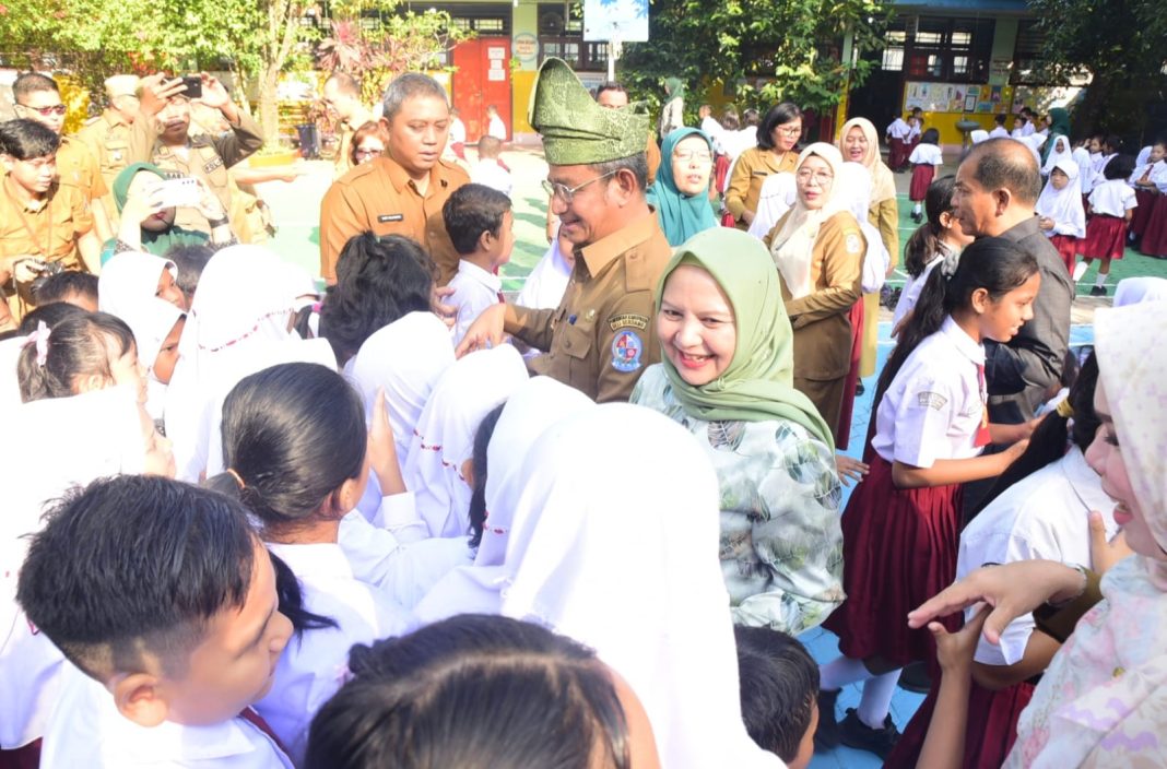 Pj Bupati Deliserdang Wiriya Alrahman bersama Pj Ketua TP PKK Ny Ismiralda Wiriya menyalami pelajar di Tanjungmorawa, Selasa (23/7/2024). (Dok/Kominfo Deliserdang)