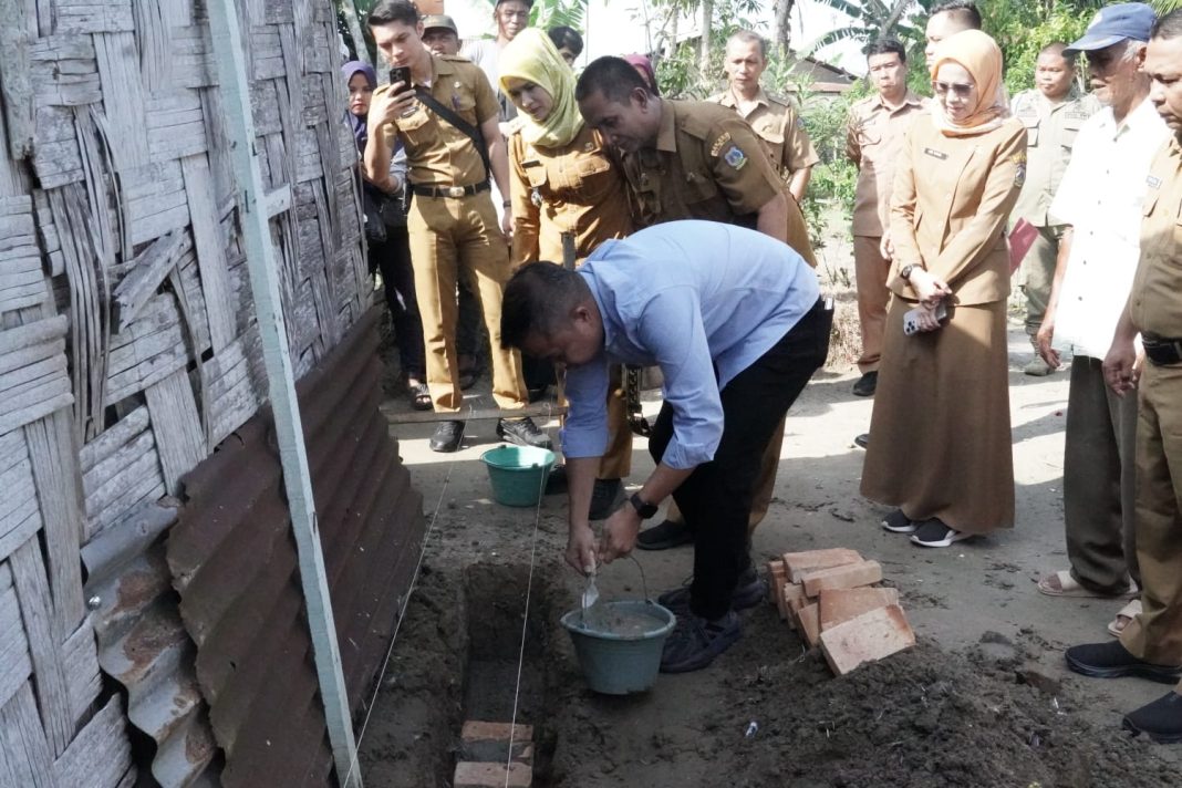 Pj Wali Kota Tebingtinggi Dr Moettaqien Hasrimi saat meletakkan batu pertama perbaikan RTLH milik Bapak Wagimin dan Ibu Parida Hanum di Jalan Merpati Lingkungan II, Kelurahan Pinang Mancung, Kecamatan Bajenis, Selasa (30/7/2024). (Dok/Kominfo Tebingtinggi)