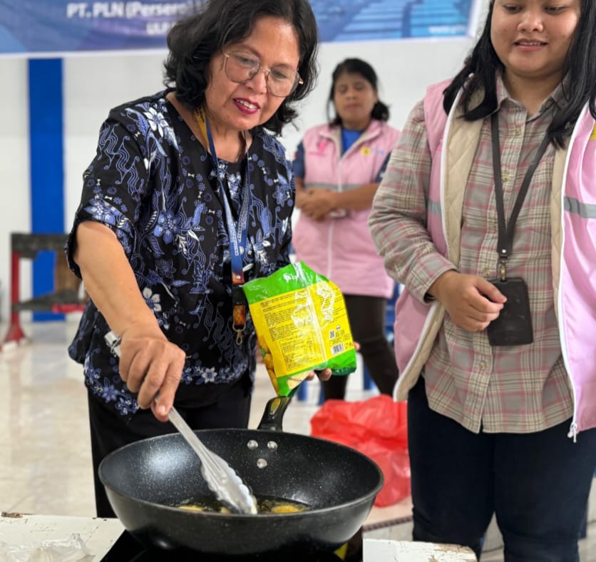 Kepala Sekolah SMK YP Parulian Tobasa Jetty Situmorang disaksikan Manager PLN ULP Porsea, Martha Retniati memasak menggunakan kompor induksi, Jumat (2/8/2024).