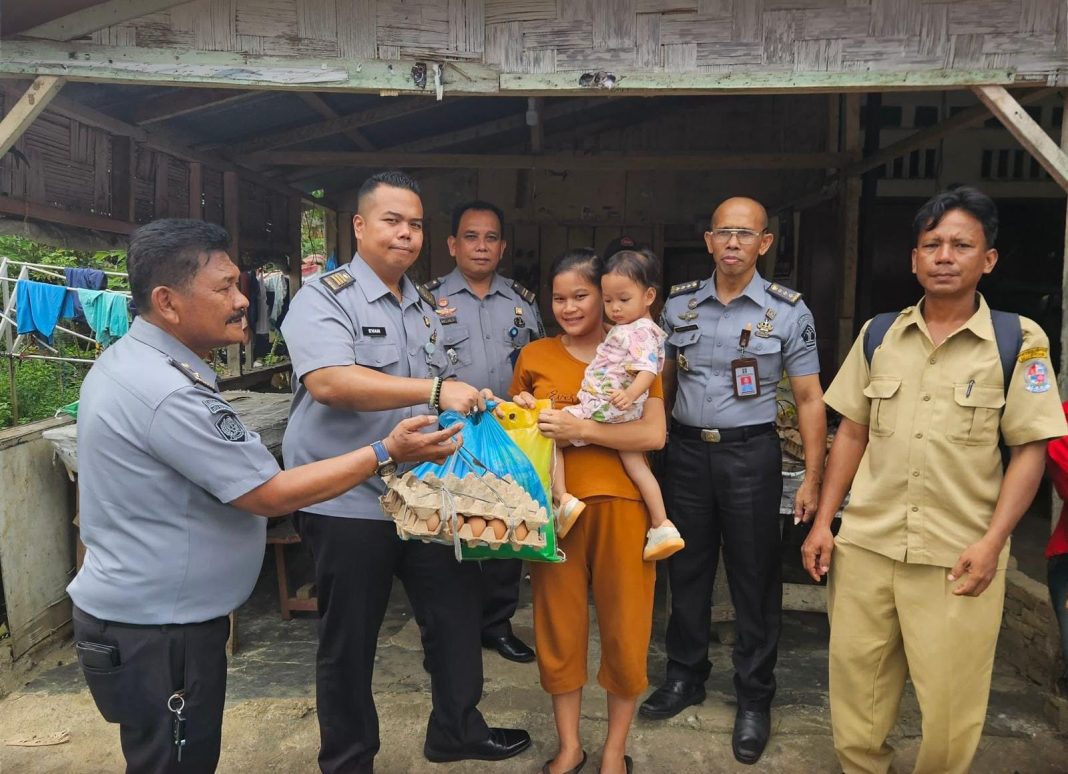 Plt Kepala Lapas Kelas IIA Pancurbatu Kriston Napitupulu berfoto bersama warga saat melaksanakan bakti sosial (baksos) membagikan sembako, Senin (5/8/2024). (Dok/Lapas Pancurbatu)