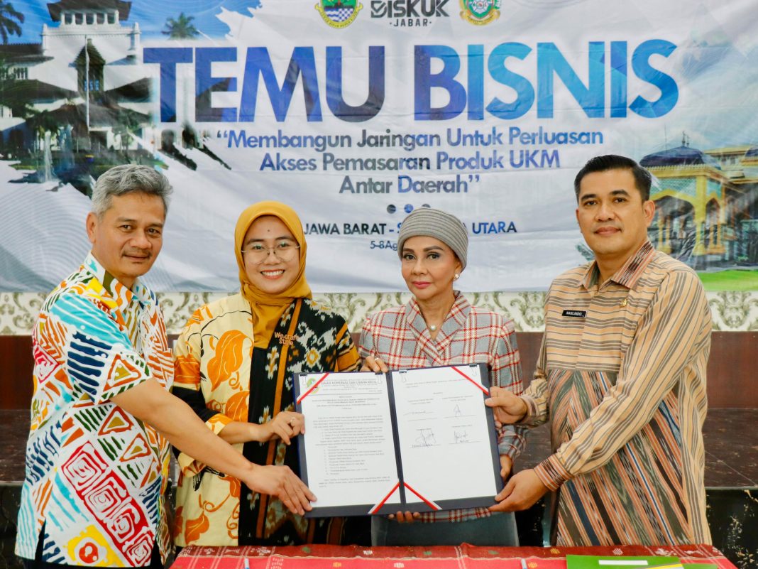 Naslindo Sirait memberikan cinderamata kepada Kadis KUK Jabar Rachmat Taufik Garsadi pada acara Temu Bisnis di Aula Gedung UPTD PLUT Sumut, Jalan Gatot Subroto Medan, Selasa (6/8/2024). (Dok/Diskop Sumut)