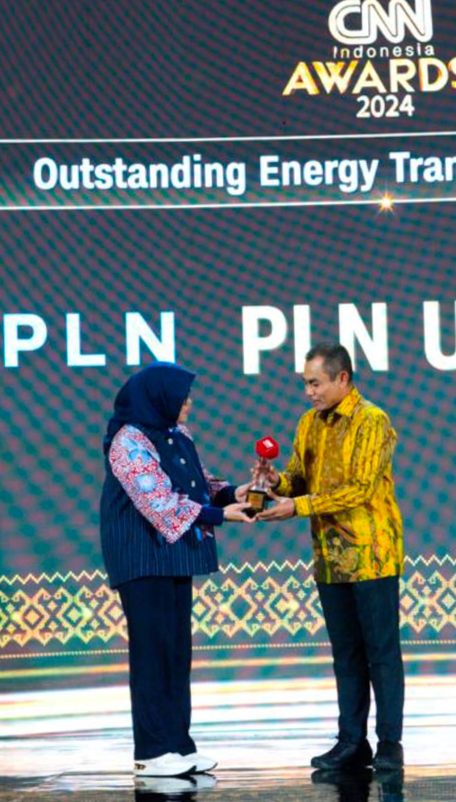 Penghargaan Outstanding Energy Transition Practices diserahkan langsung oleh Direktur Utama CNN Indonesia Titin Rosmasari (kiri), kepada General Manager PLN UID Sumut Saleh Siswanto sebagai bentuk apresiasi atas capaian luar biasa PLN dalam bidang energi terbarukan, Jumat (9/8/2024). (Dok/PLN)