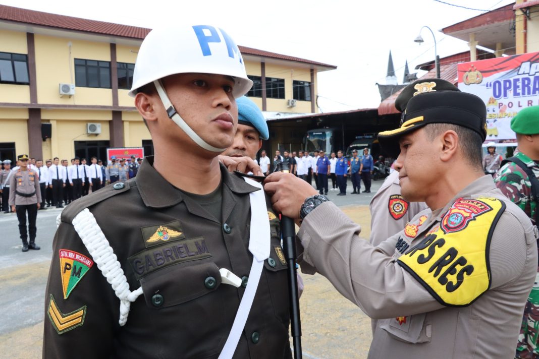 Kapolres Pematangsiantar AKBP Yogen Heroes Baruno menyematkan pita kepada perwakilan personel saat memimpin apel gelar pasukan Operasi Hatra Toba 2024 di Lapangan Mako Polres Pematangsiantar, Rabu (28/8/2024). (Dok/Polres Pematangsiantar)